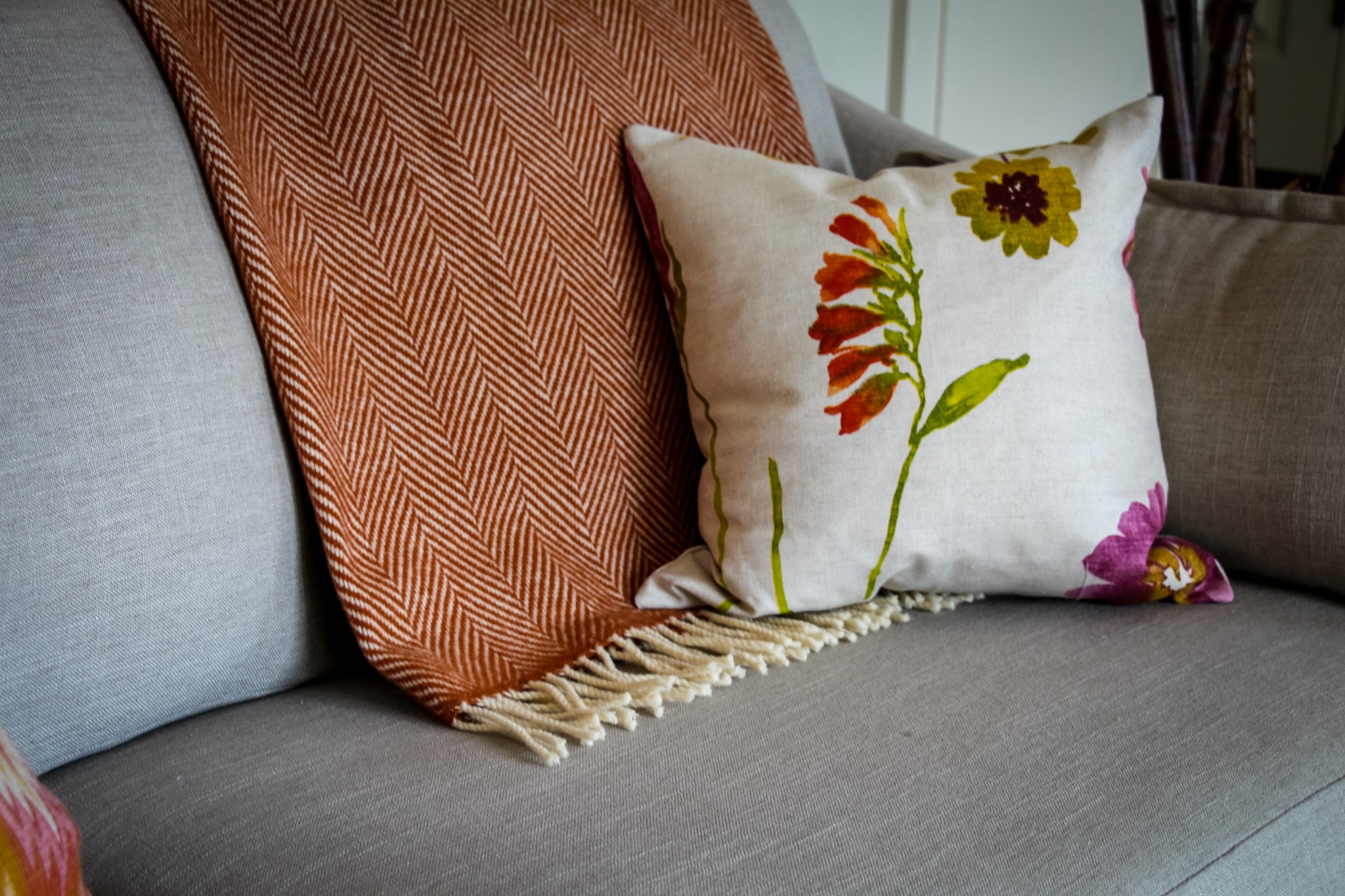 On a neutral gray sofa, a floral pillow offers a pop of seasonal colour.