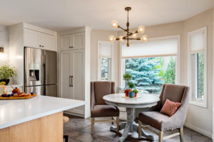 In a remodeled transitional kitchen, an open breakfast snack area great for hosting informal guests - on the left is a shallow custom cabinet that makes use of otherwise wasted space and stores cleaning tools.